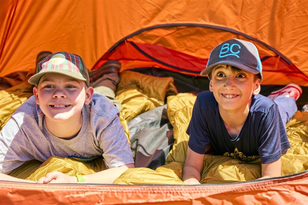 Two Cub Scouts smiling together at a campsite